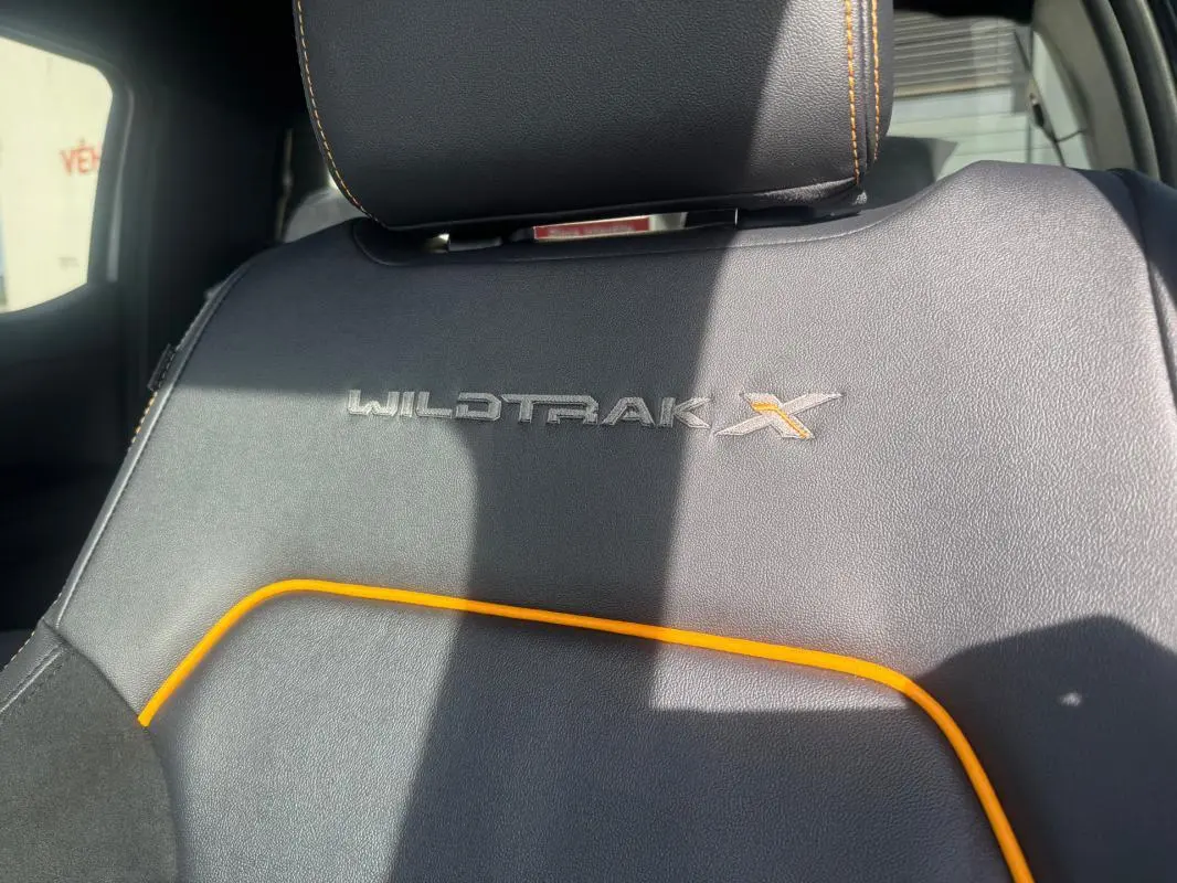 Gros plan sur le siège avant noir avec surpiqûres orange et logo Wildtrak X brodé du Ford Ranger gris.