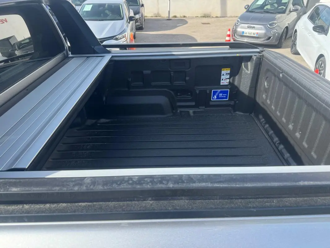 Vue rapprochée de la benne arrière grise d’un Ford Ranger 2025 avec barres de toit et ridelle ouverte.