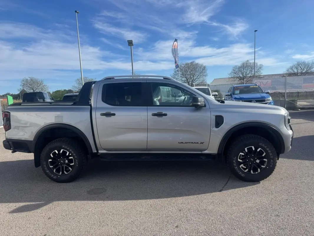 Vue latérale droite d'un Ford Ranger gris 2025 Wildtrak X avec jantes alliage 17 pouces et barres de toit.
