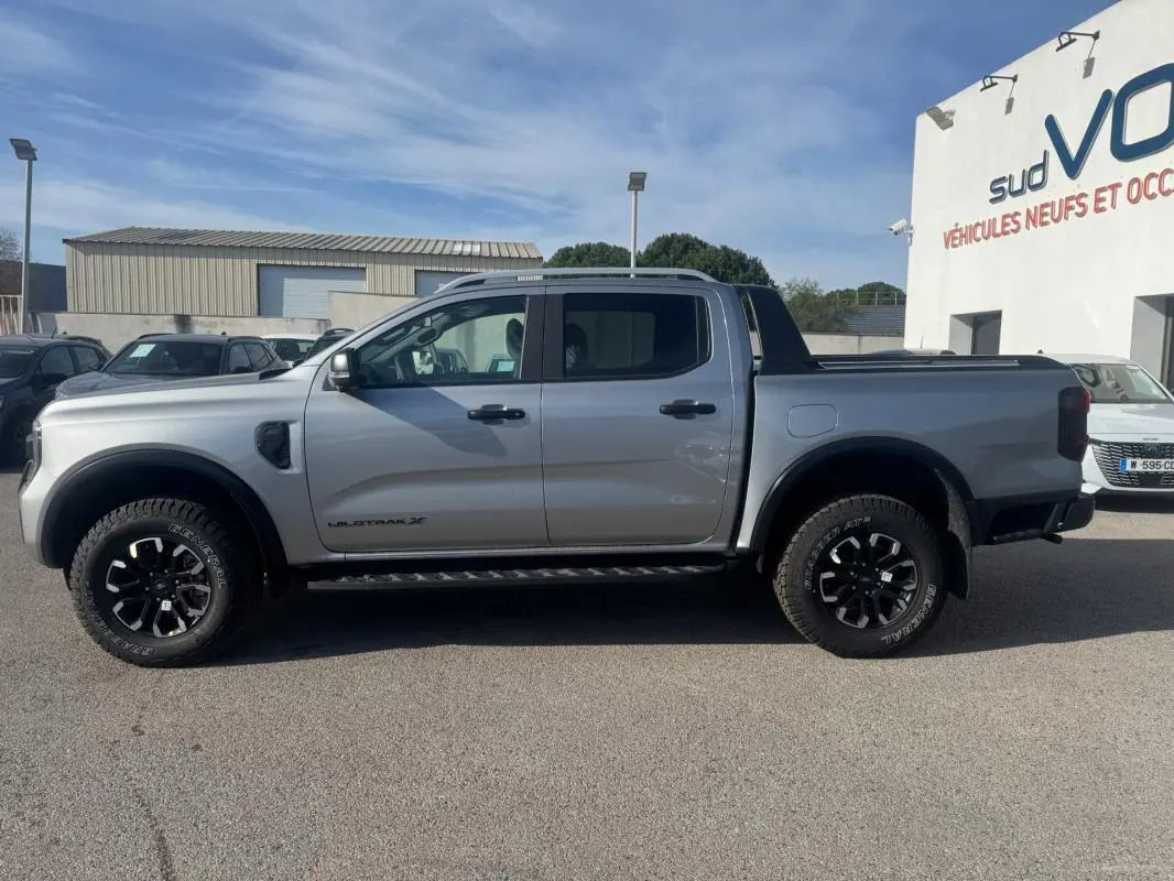 Vue de profil côté gauche d'un Ford Ranger gris 2025 double cabine avec jantes alliage noires et vitres surteintées.