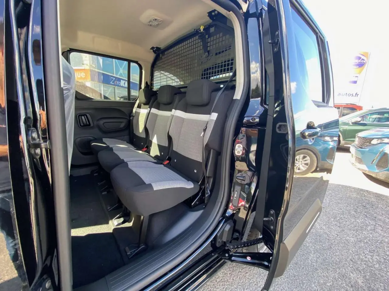 Vue latérale droite du Citroën Berlingo noir 2026 avec porte coulissante ouverte montrant les sièges arrière et la grille de séparation.