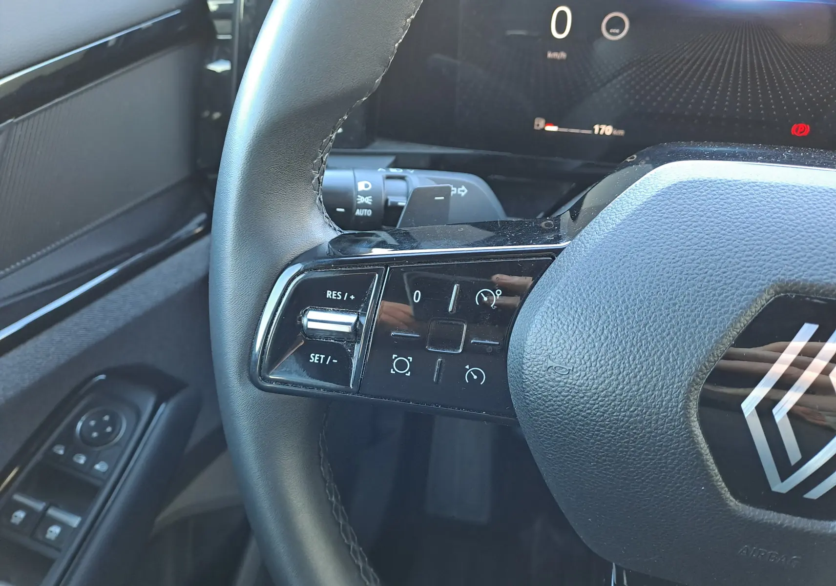 Gros plan sur le volant à gauche du Renault Austral gris schiste 2023, avec commandes intégrées et tableau de bord numérique.