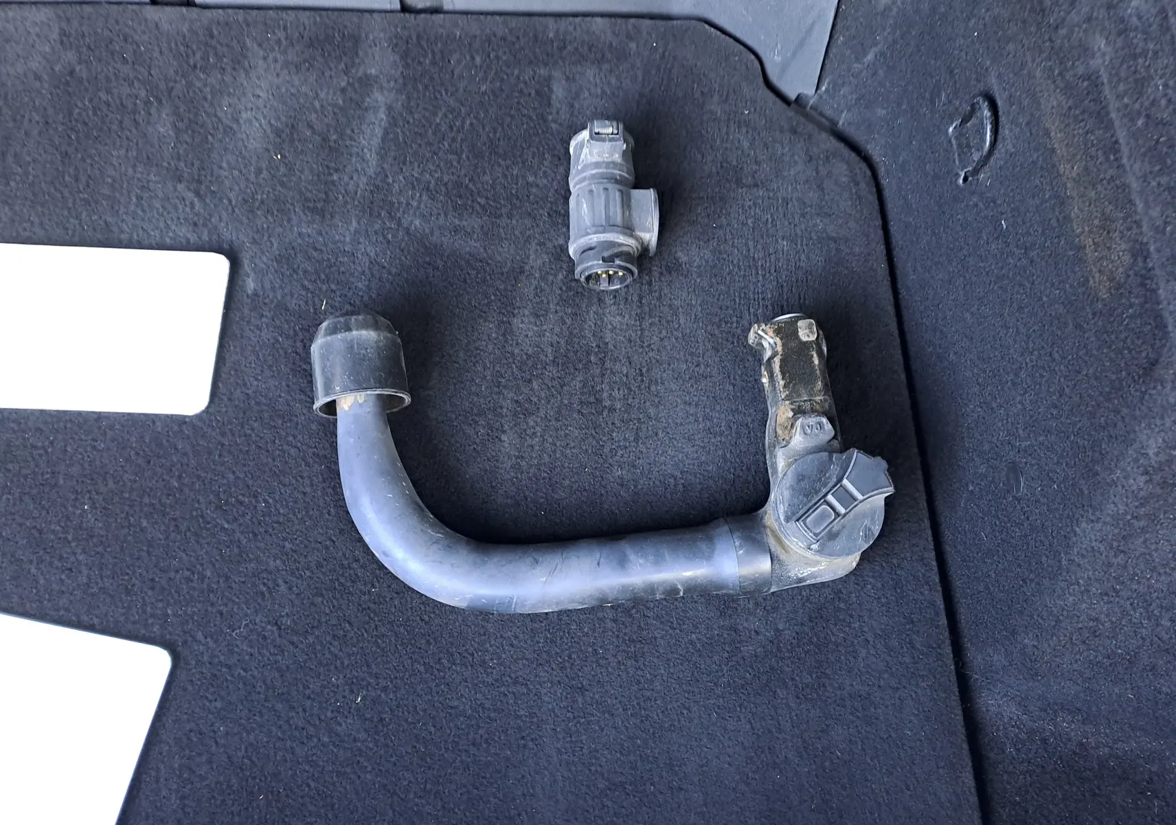 Gros plan sur attelage amovible posé sur le tapis noir du coffre d’un Renault Austral gris schiste 2023.