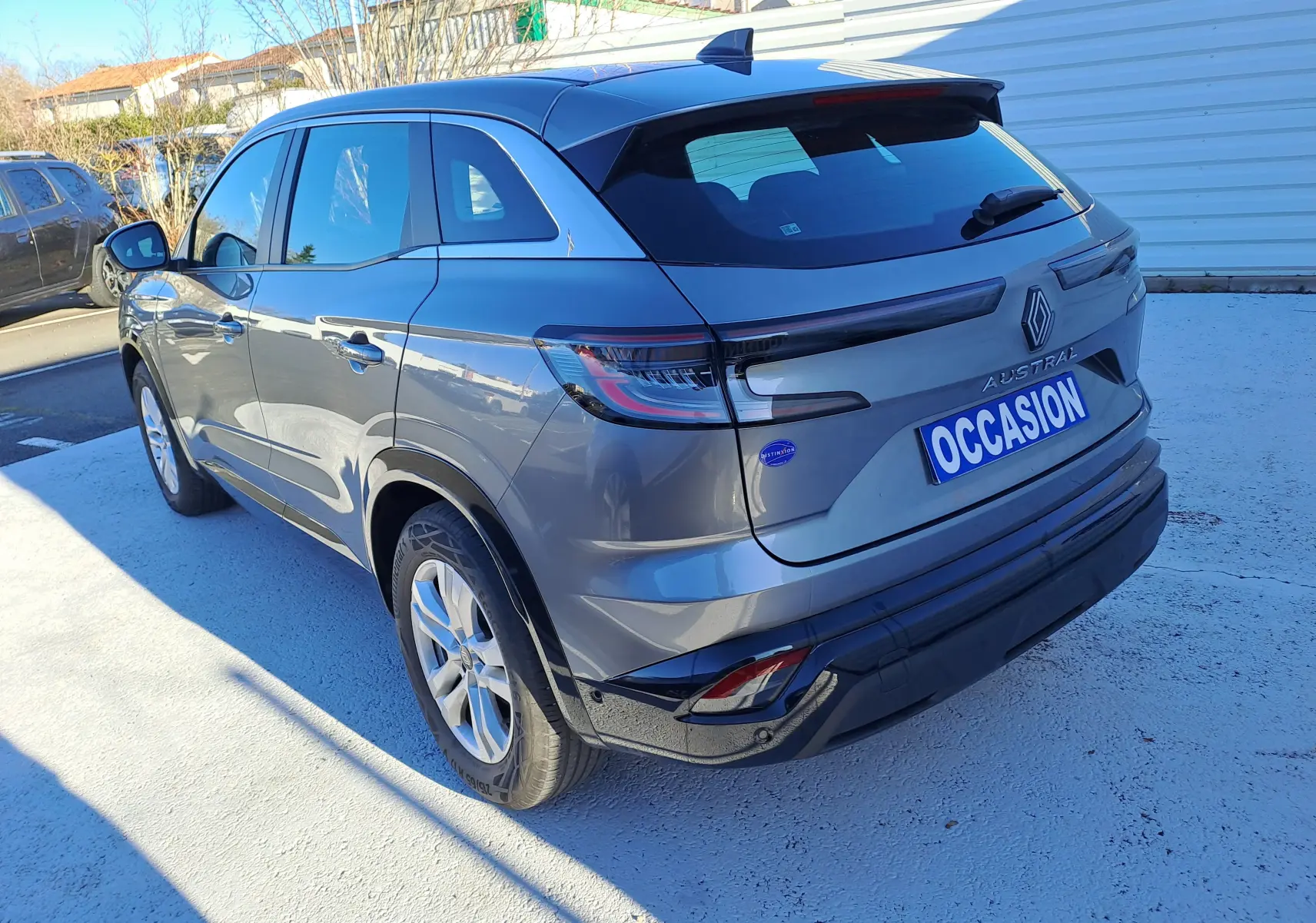 Vue 3/4 arrière droite d'un Renault Austral gris schiste avec feux arrière LED et plaque "OCCASION" visible.