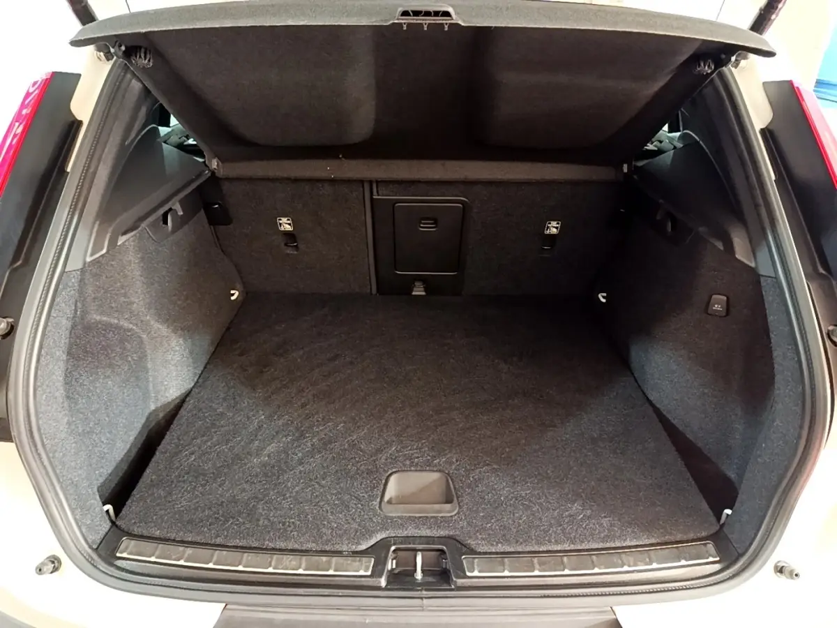 Coffre ouvert vu de l'arrière du Volvo XC40 Recharge T5 262 DCT7 Plus, intérieur noir et moquette épaisse.