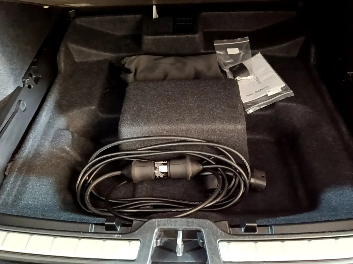 Vue plongeante sur le coffre noir d'un Volvo XC40 Recharge T5 262 avec câble de charge et accessoires rangés.