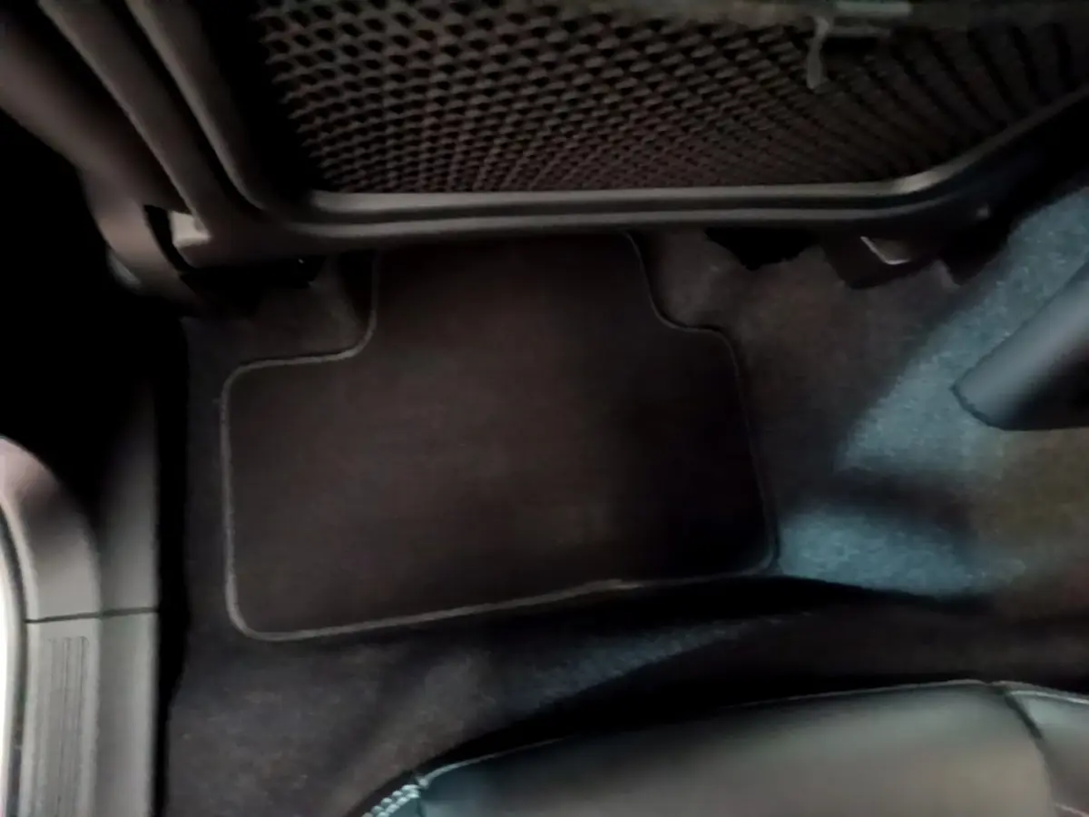 Vue rapprochée du tapis de sol noir côté passager avant du Volvo XC40 Recharge T5 2023, intérieur sombre.