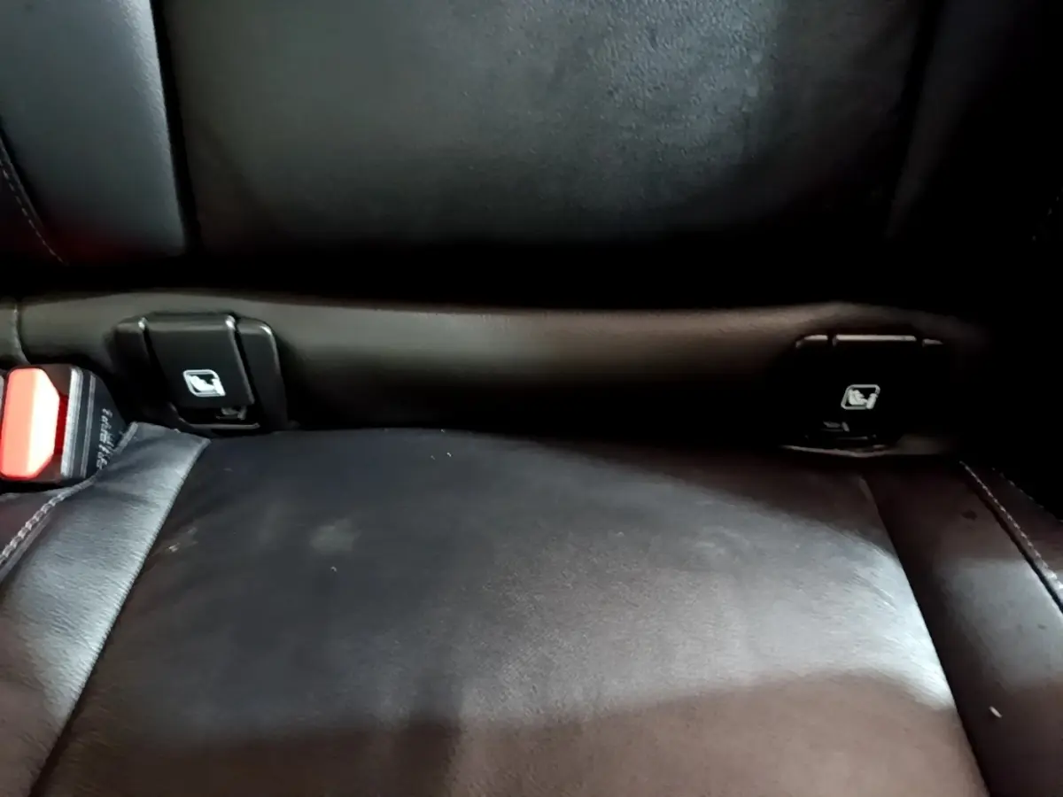 Gros plan sur la banquette arrière noire en cuir du Volvo XC40 Recharge T5, montrant les fixations Isofix et la ceinture de sécurité.