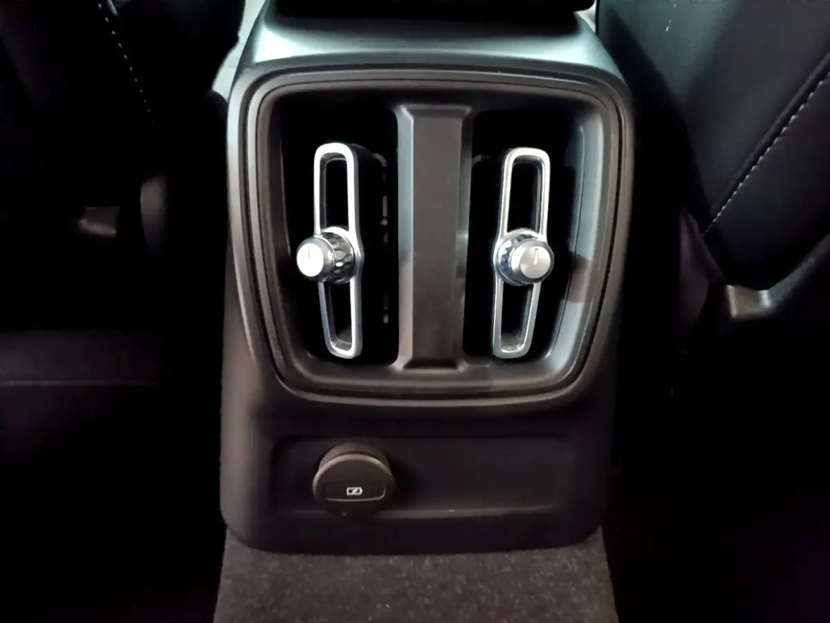Gros plan sur les aérateurs arrière chromés et prise USB dans l’habitacle noir du Volvo XC40 Recharge T5 2023.