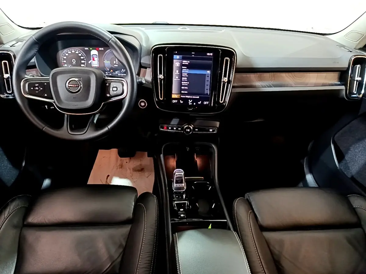 Vue intérieure avant du Volvo XC40 Recharge T5 262 DCT7 Plus 2023, tableau de bord noir avec écran tactile central et volant cuir.