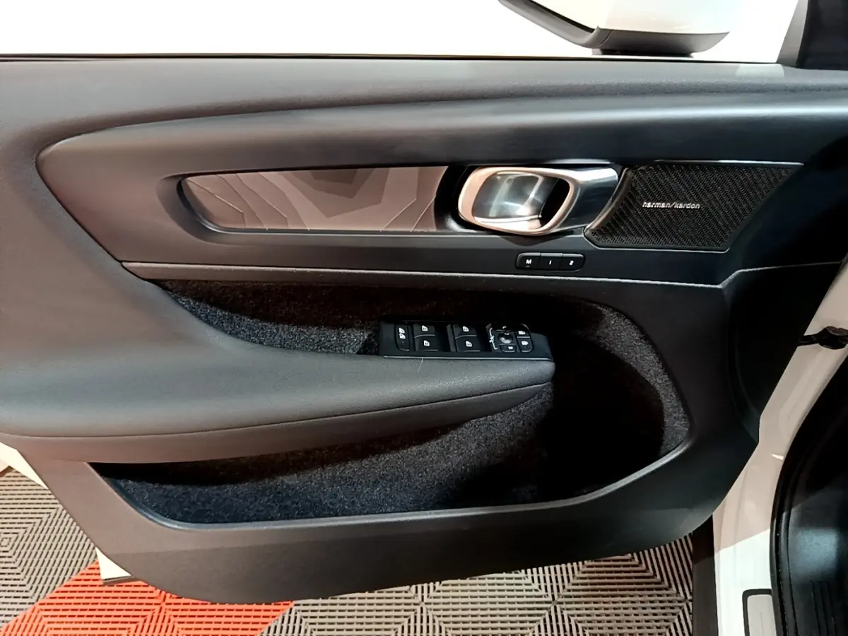 Vue intérieure côté gauche de la porte avant d’un Volvo XC40 blanc avec panneau noir et haut-parleur Harman/Kardon.