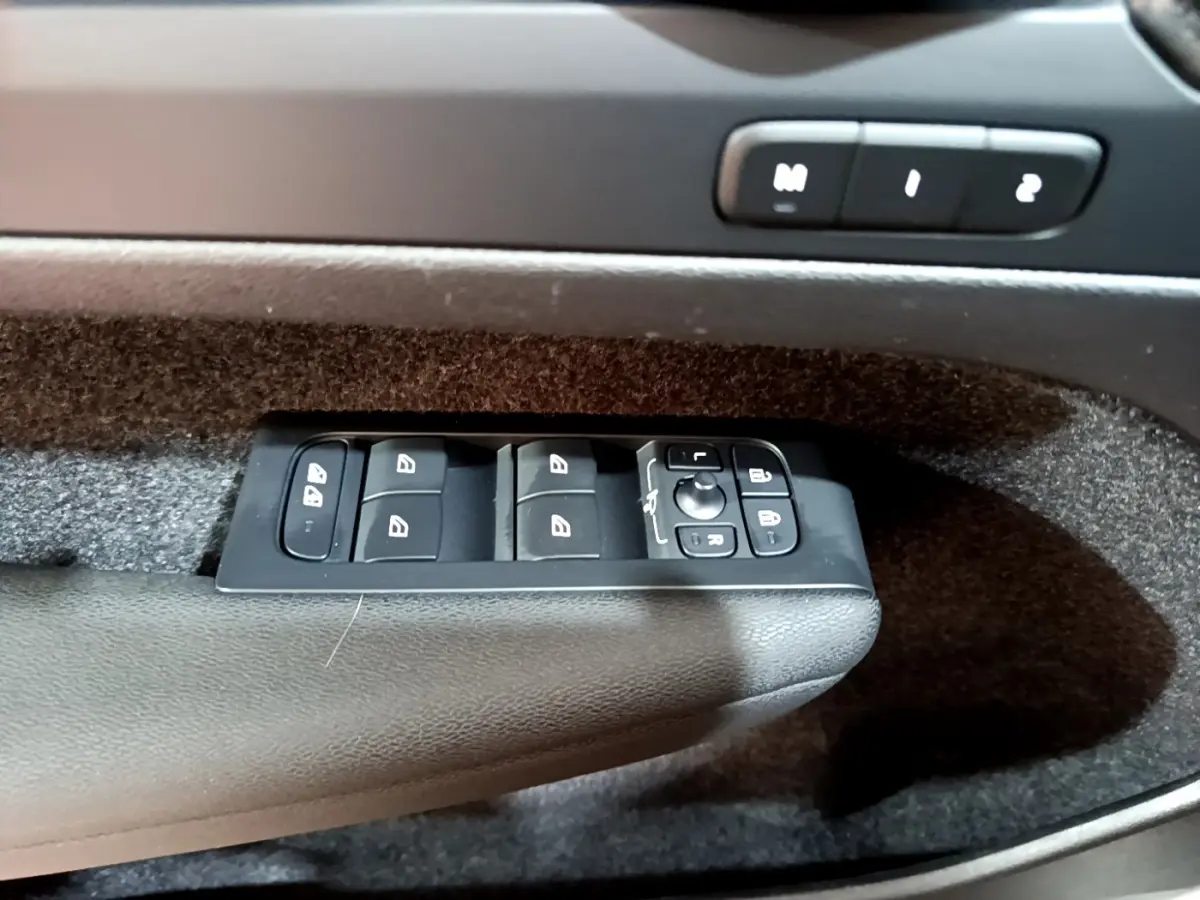 Gros plan sur les commandes de lève-vitres et réglages des rétroviseurs côté gauche intérieur d’un Volvo XC40 2023 hybride rechargeable.