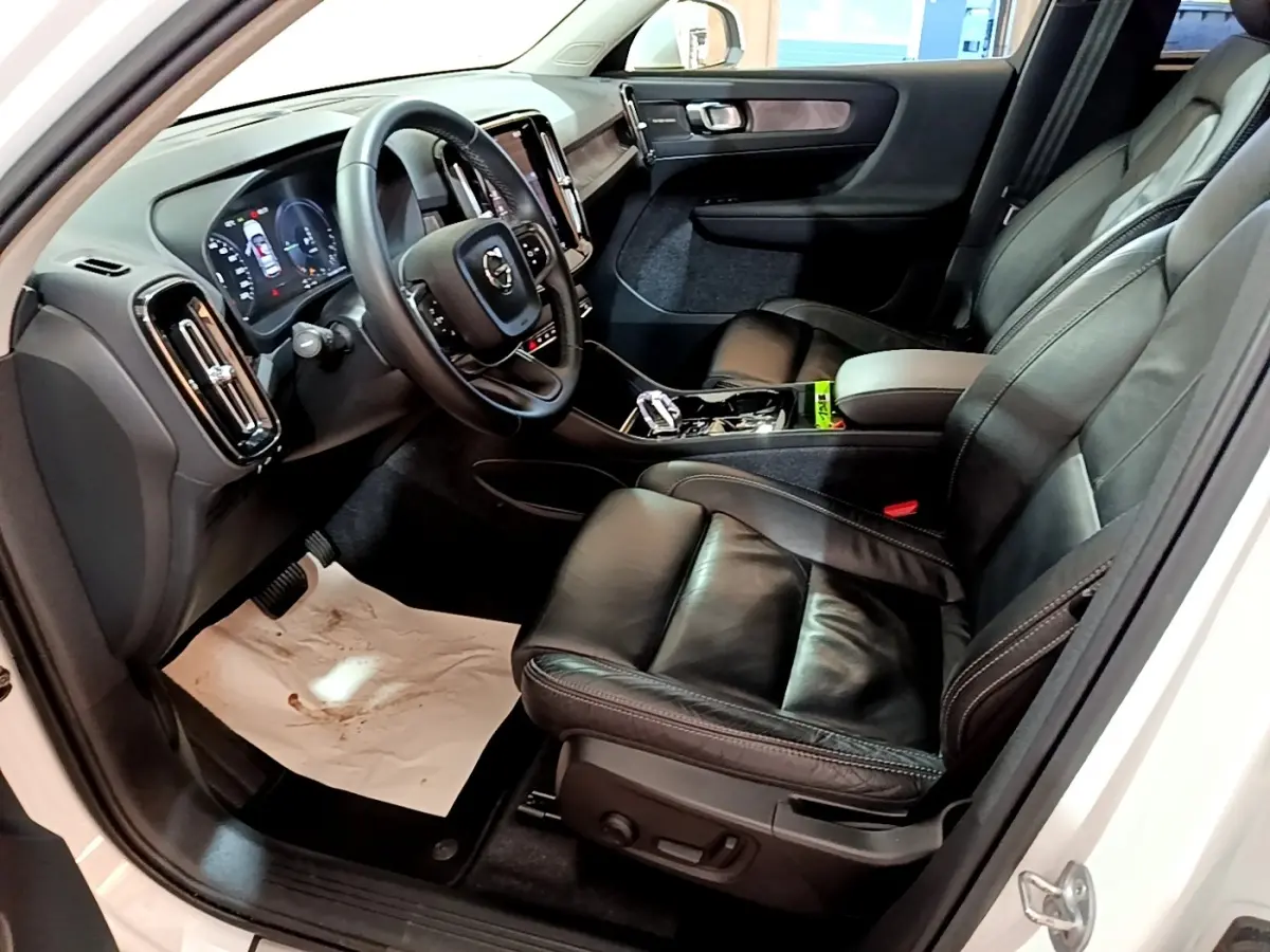 Vue intérieure côté conducteur du Volvo XC40 Recharge T5 262 DCT7 Plus 2023, sièges cuir noir et tableau de bord moderne.