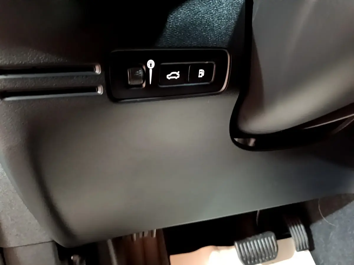 Détail intérieur montrant les commandes d’ouverture du coffre et du réservoir sur un Volvo XC40 hybride rechargeable 2023.