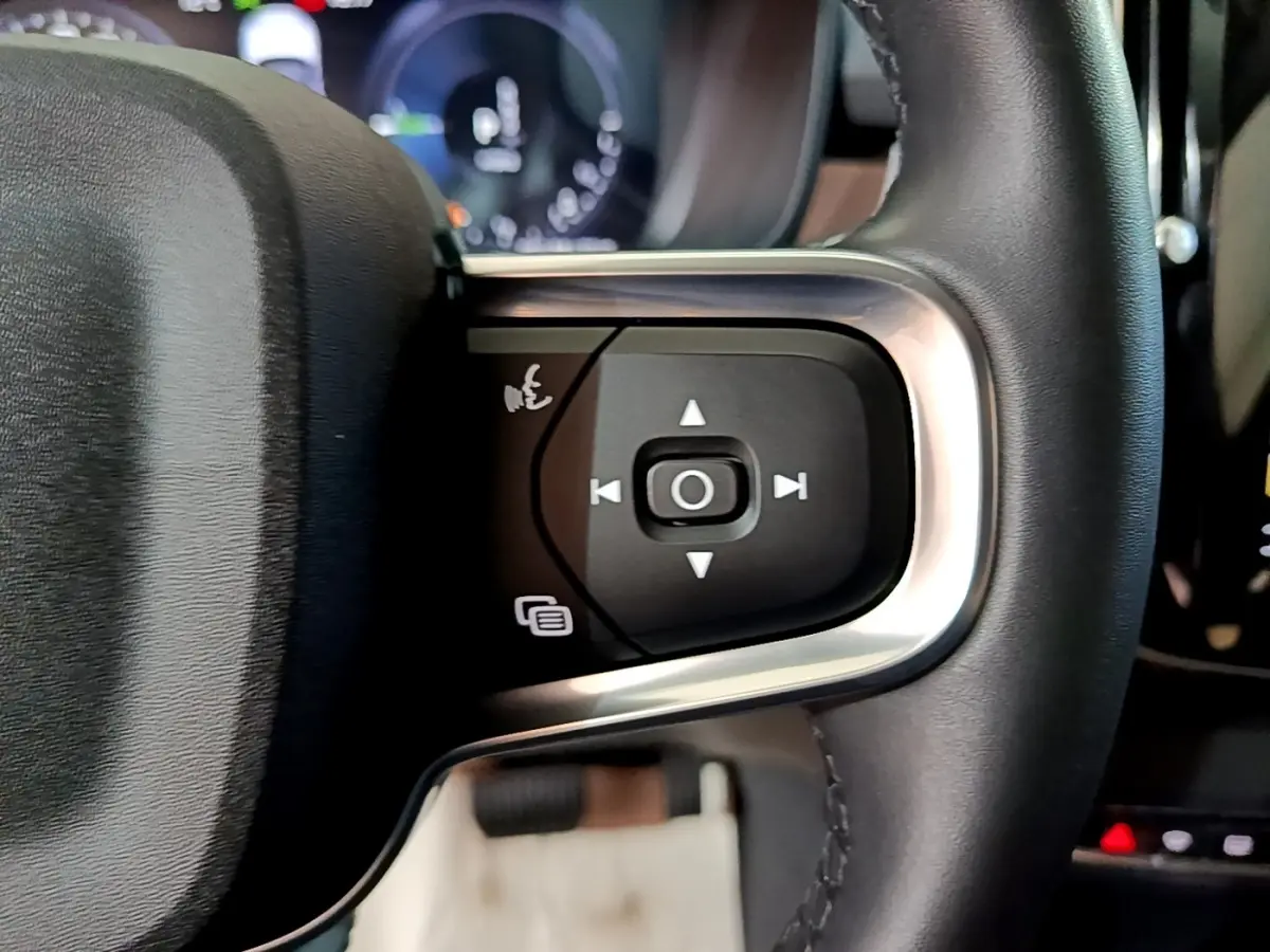 Gros plan sur les commandes noires et argentées du volant cuir noir du Volvo XC40 Recharge T5 2023.