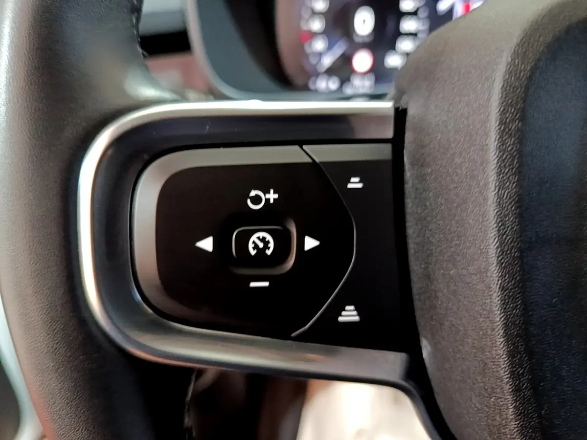 Gros plan sur les commandes du régulateur de vitesse au volant noir et argent du Volvo XC40 hybride rechargeable.