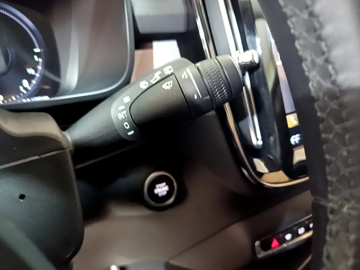 Gros plan sur la manette d’essuie-glace et le bouton démarrage du tableau de bord noir du Volvo XC40 hybride rechargeable.