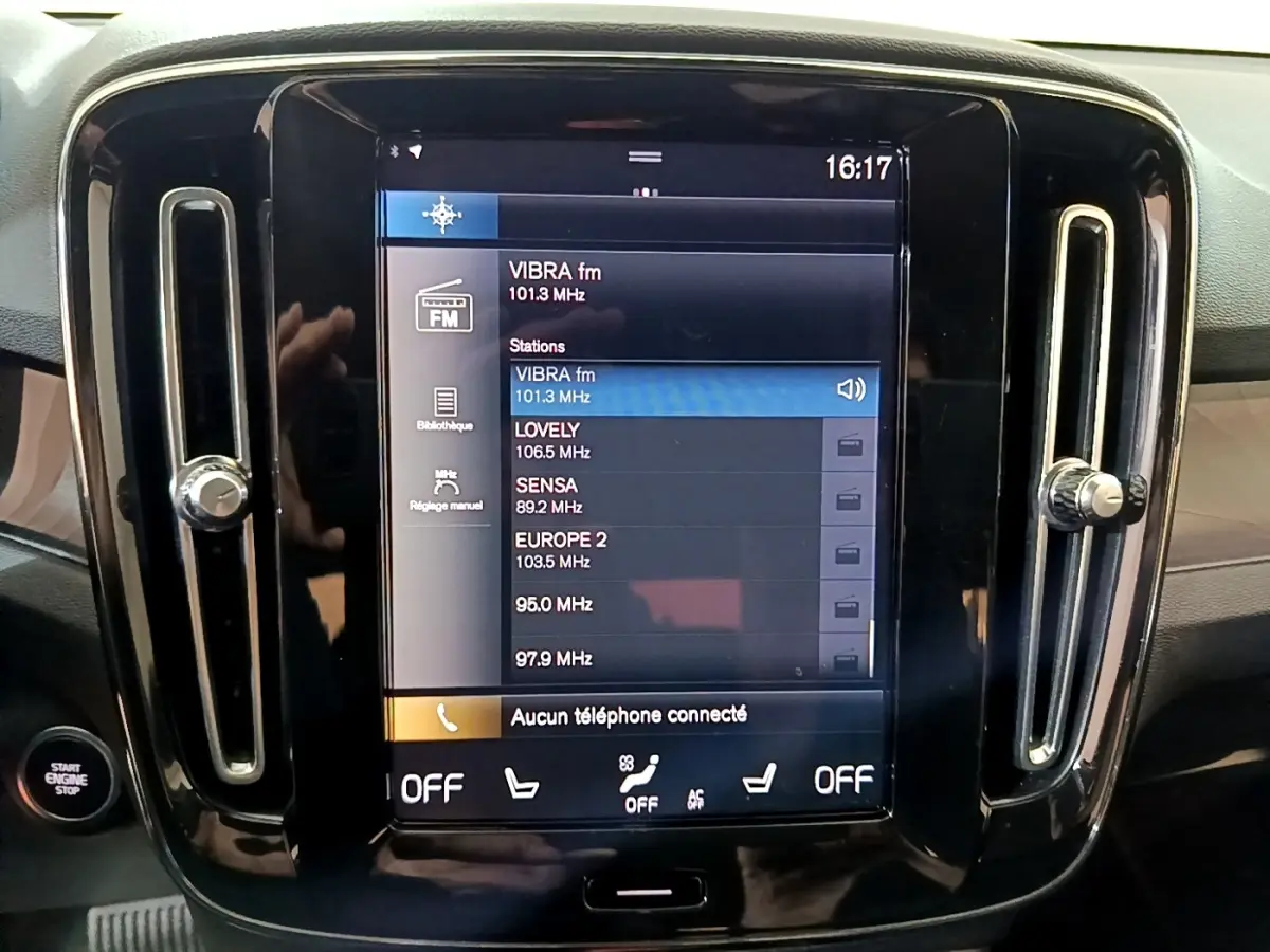 Vue frontale du tableau de bord noir du Volvo XC40 Recharge T5 avec écran tactile central affichant les stations radio.