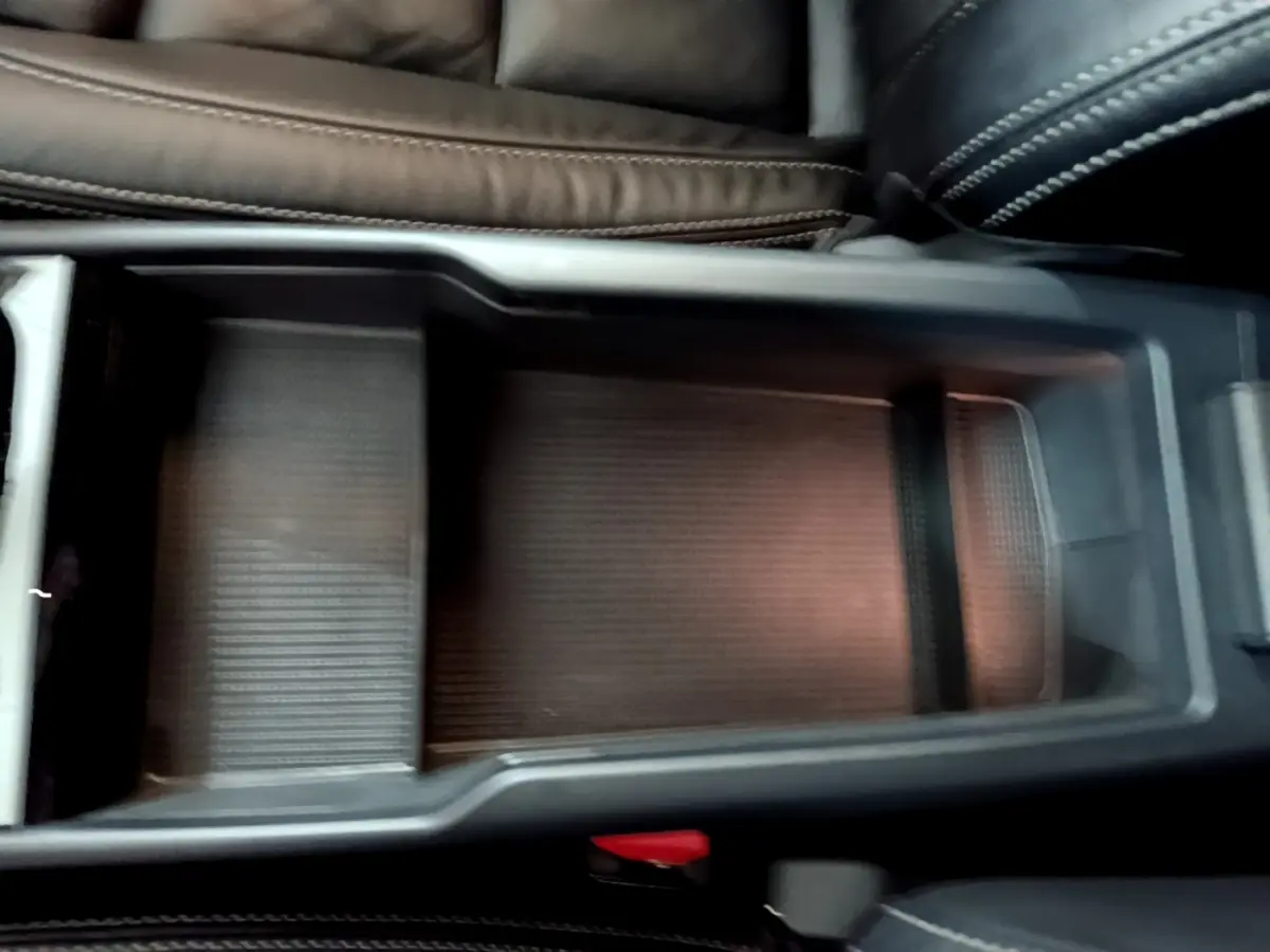 Vue rapprochée de la console centrale noire avec rangement ouvert et sellerie cuir sombre du Volvo XC40 Recharge T5 2023.