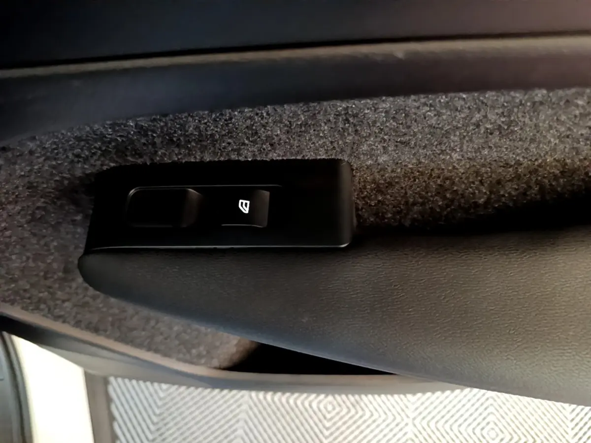 Détail du bouton de commande de vitre électrique sur la porte intérieure noire d’un Volvo XC40 hybride rechargeable.