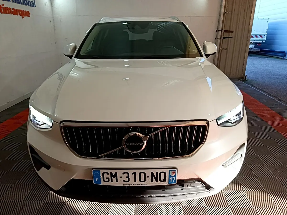 Vue frontale d'un Volvo XC40 Recharge T5 blanc avec calandre noire et phares LED allumés en intérieur.