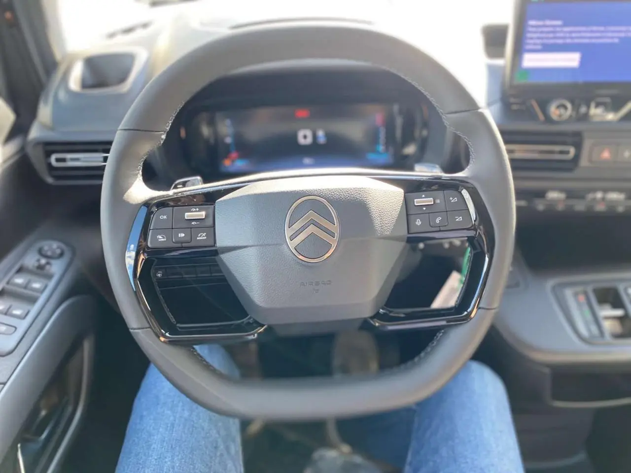 Vue intérieure centrée sur le volant multifonction noir du Citroën Berlingo avec tableau de bord et écran tactile en arrière-plan.