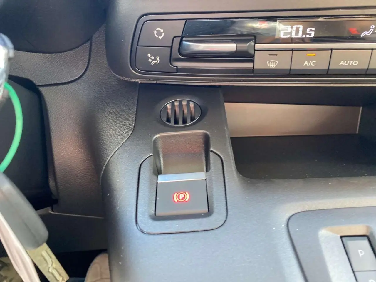 Détail intérieur du frein de stationnement électrique et commandes de climatisation du Citroën Berlingo noir 2026.