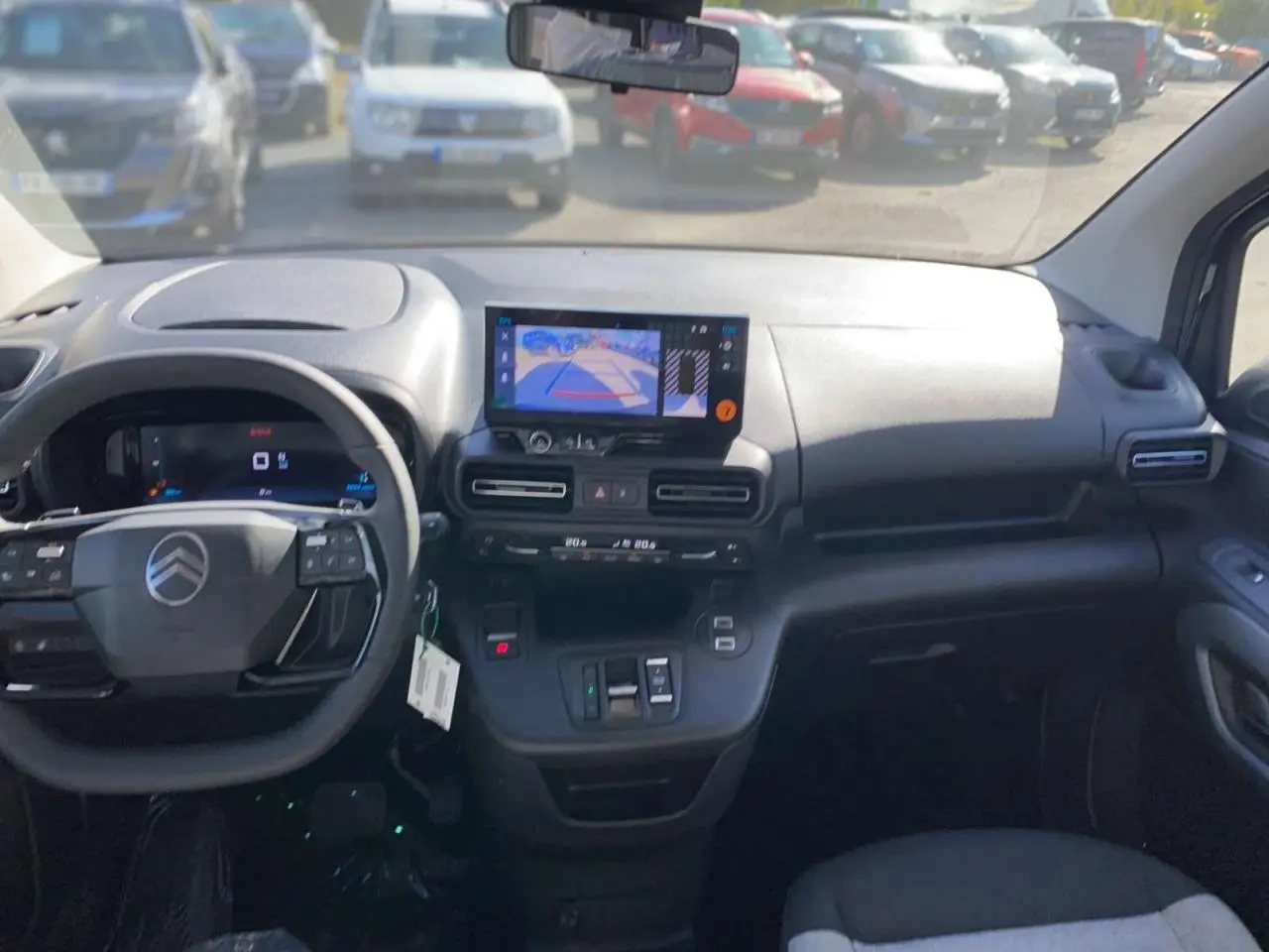 Vue intérieure avant du Citroën Berlingo 2026 noir, tableau de bord avec écran de caméra de recul et volant multifonction.