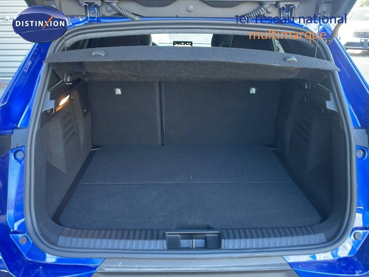 Coffre ouvert vu de l'arrière d'une Renault Symbioz bleu iron metal, montrant un espace de chargement propre et spacieux.