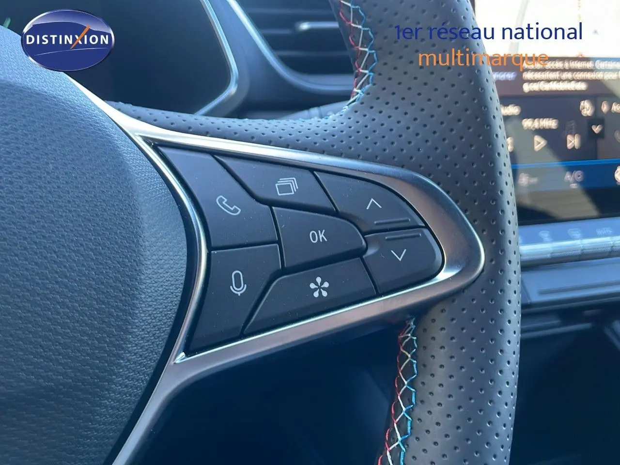 Gros plan sur les commandes gauche du volant en cuir perforé avec surpiqûres tricolores du Renault Symbioz bleu iron metal.