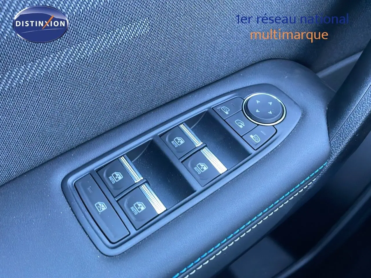Gros plan sur les commandes des vitres électriques côté conducteur avec surpiqûres bleues dans une Renault Symbioz bleu iron metal.