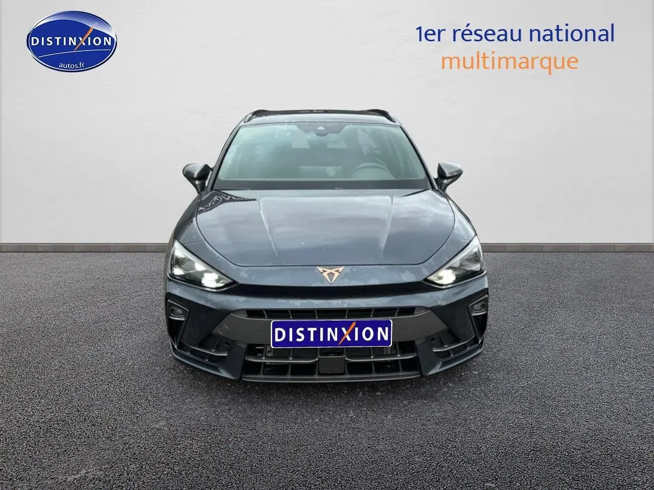 Vue frontale d'une CUPRA Leon ST 2025 gris magnétique avec phares LED allumés et logo distinctif sur calandre.