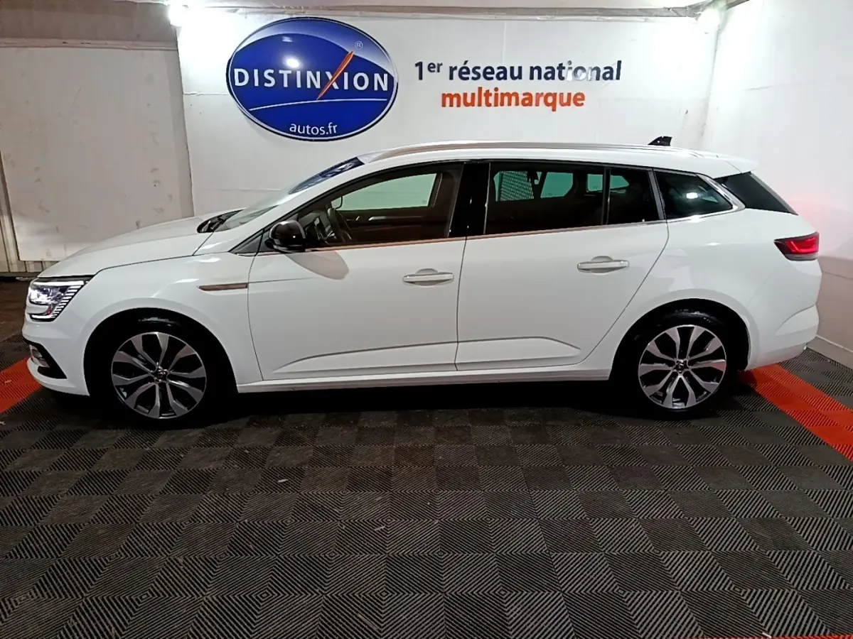 Profil côté gauche d'une Renault Mégane Techno TCe 140 EDC blanche, avec jantes alliage et feux LED visibles.