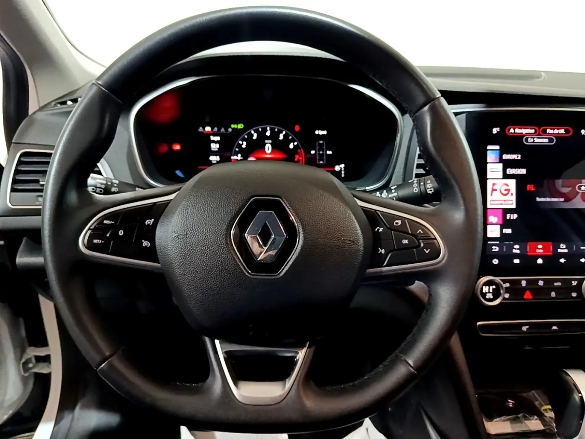 Vue rapprochée du volant noir avec logo Renault au centre et tableau de bord digital de la Renault Mégane 2023.