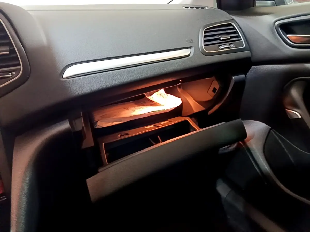 Intérieur de la Renault Mégane Techno TCe 140 2023, vue du côté passager avec boîte à gants ouverte et éclairage intérieur.