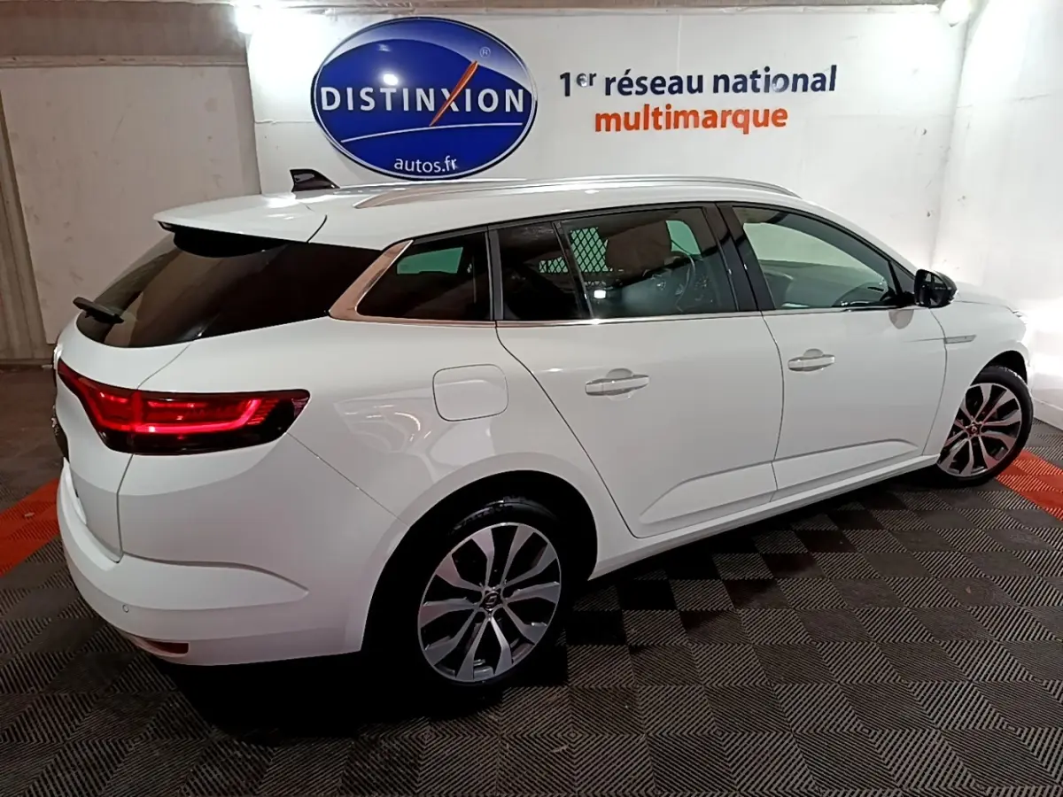Renault Mégane Techno TCe 140 blanc vue 3/4 arrière droit, feux LED allumés et jantes alliage visibles.