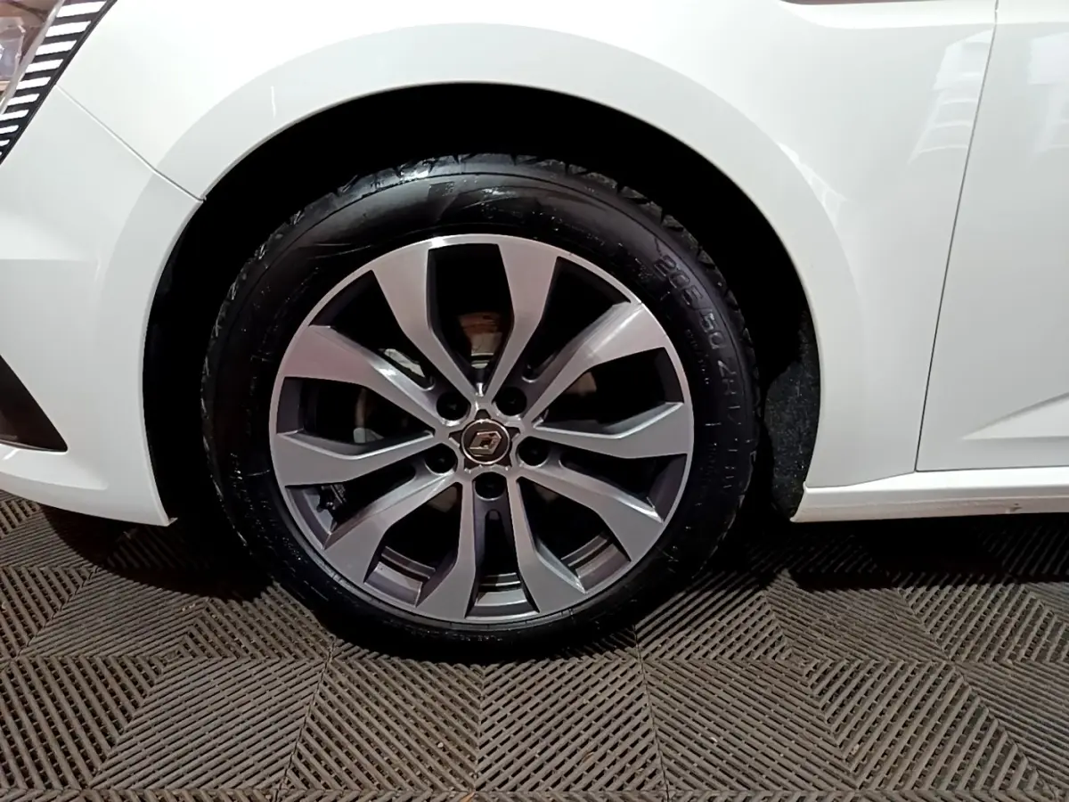 Gros plan sur la roue avant gauche de la Renault Mégane Techno TCe 140 EDC blanche avec jante alliage distinctive.