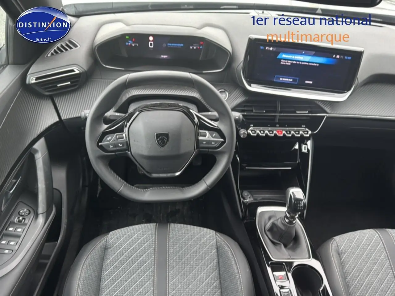 Vue intérieure frontale du poste de conduite du Peugeot 2008 gris sélénite avec volant compact et écran tactile central.