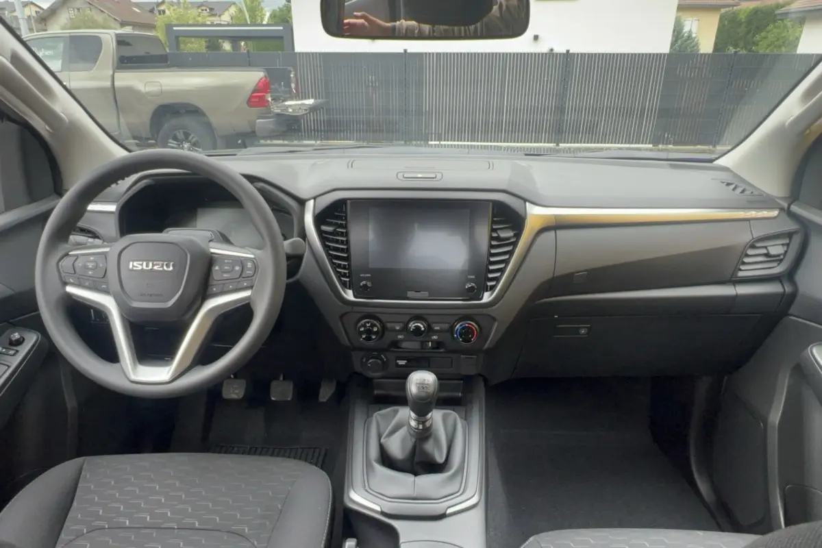 Vue intérieure avant de l'Isuzu D-MAX 2026 avec tableau de bord noir et volant multifonctions.
