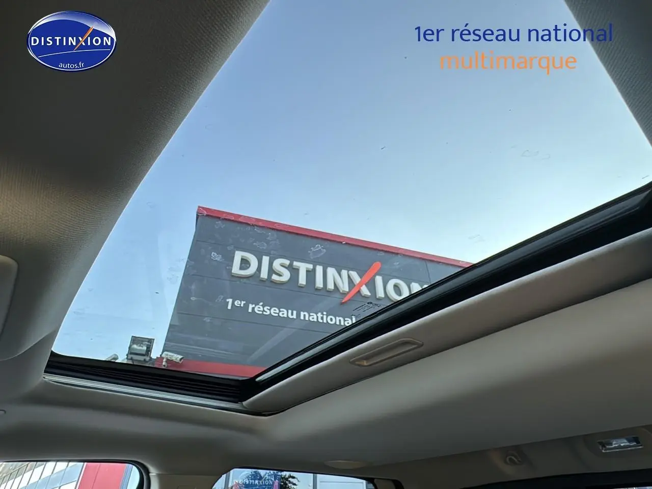 Vue intérieure du toit ouvrant panoramique du Dodge RAM 5.7 V8 noir, montrant le ciel et une enseigne extérieure.