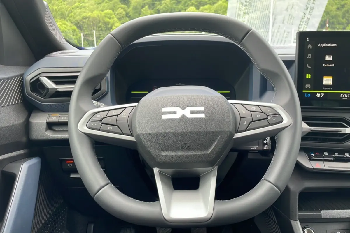 Vue rapprochée du volant cuir du Dacia Bigster 2025 avec commandes intégrées et écran tactile central visible à droite.