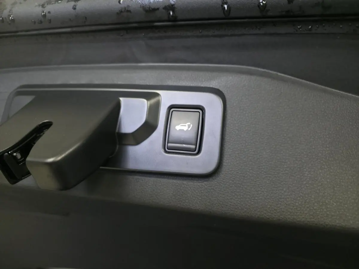 Bouton d'ouverture électrique du hayon sur panneau intérieur noir du Renault Espace gris 2025 hybride