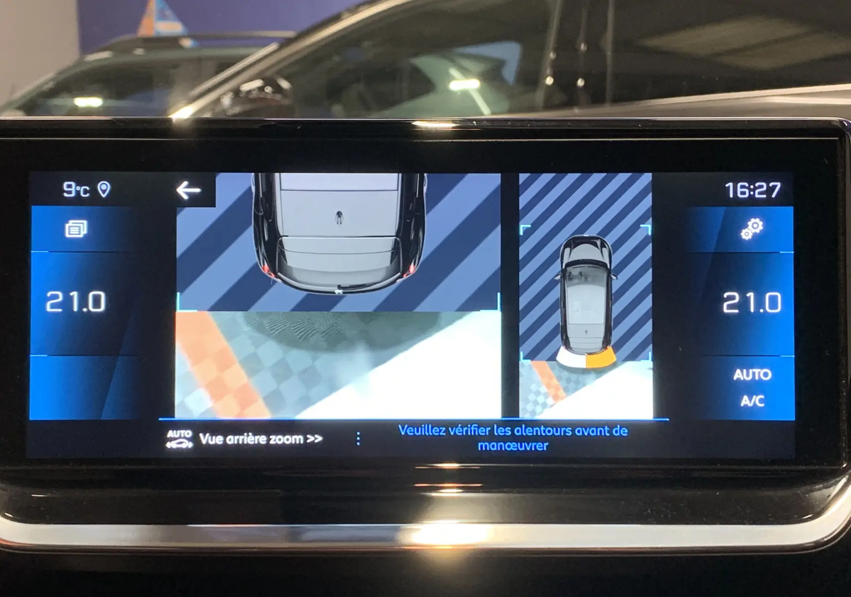 Écran de la caméra de recul et GPS de la Peugeot 208 gris, affichant une vue arrière avec indications de stationnement.