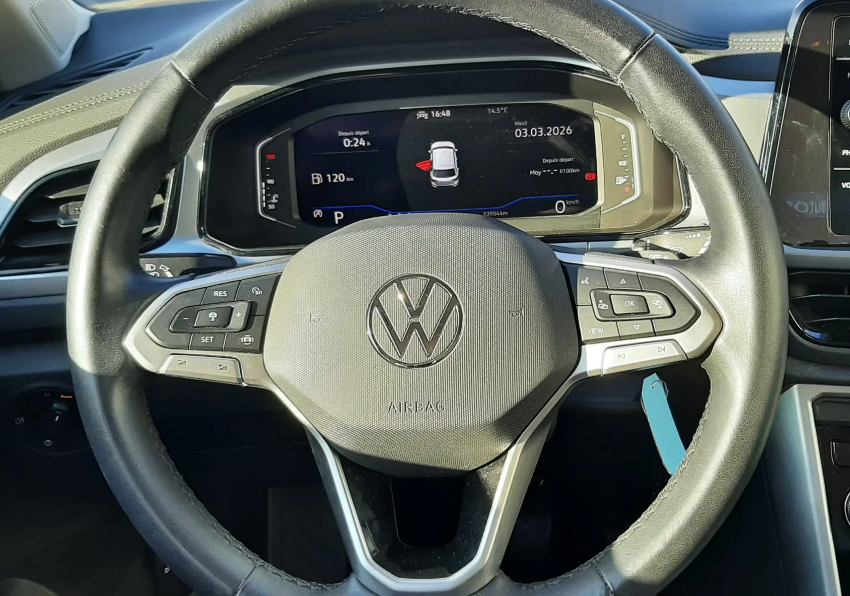 Vue centrée sur le volant noir du Volkswagen T-Roc 2022 avec tableau de bord digital allumé en arrière-plan.