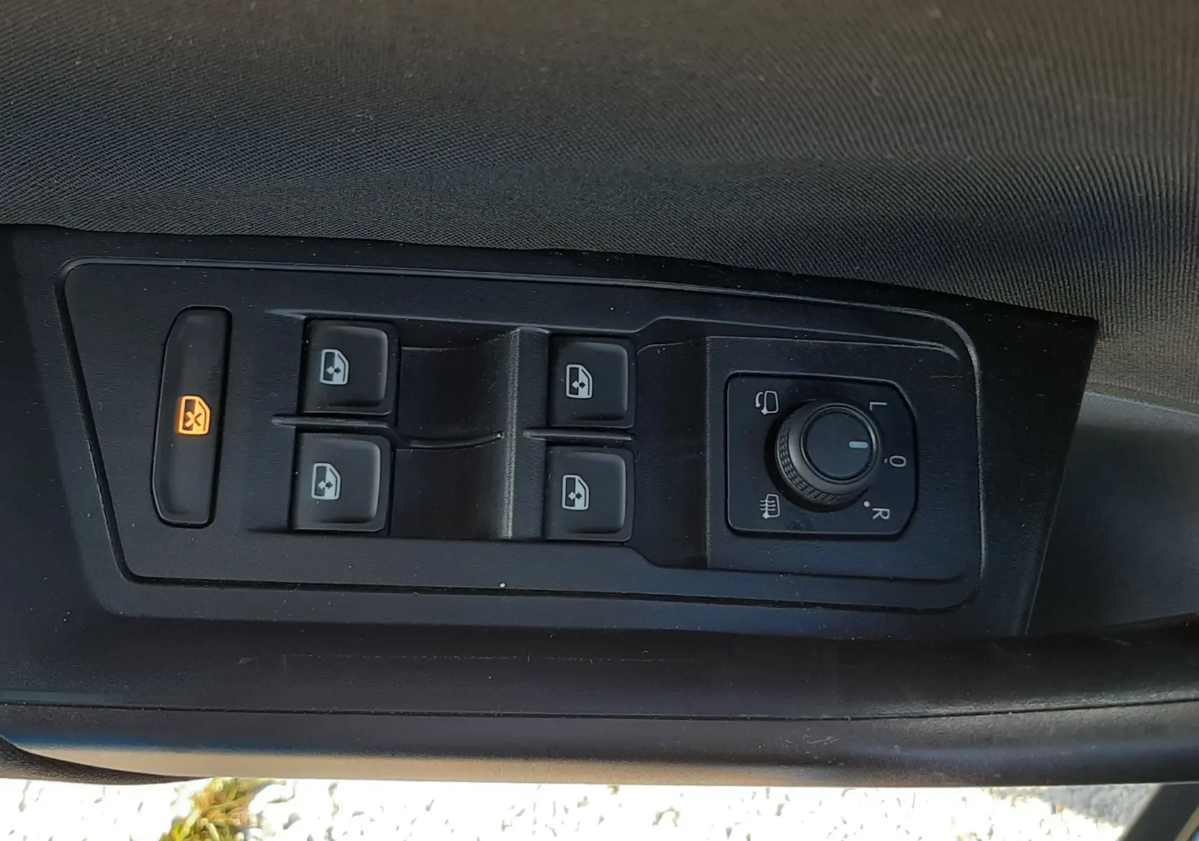 Gros plan sur les commandes de lève-vitres et réglage des rétroviseurs côté conducteur du Volkswagen T-Roc bleu 2022.