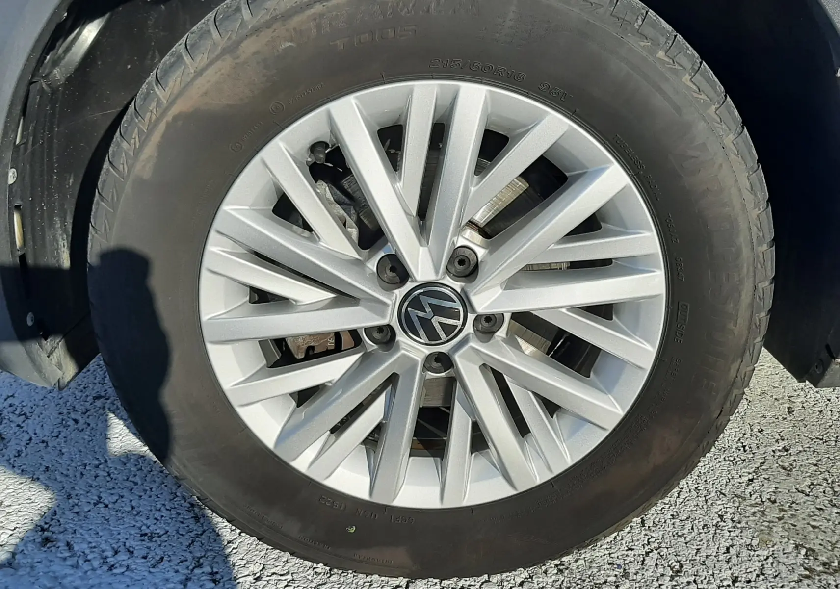 Gros plan sur la roue avant droite d’un Volkswagen T-Roc bleu 2022 avec jante alliage argentée à multiples branches.