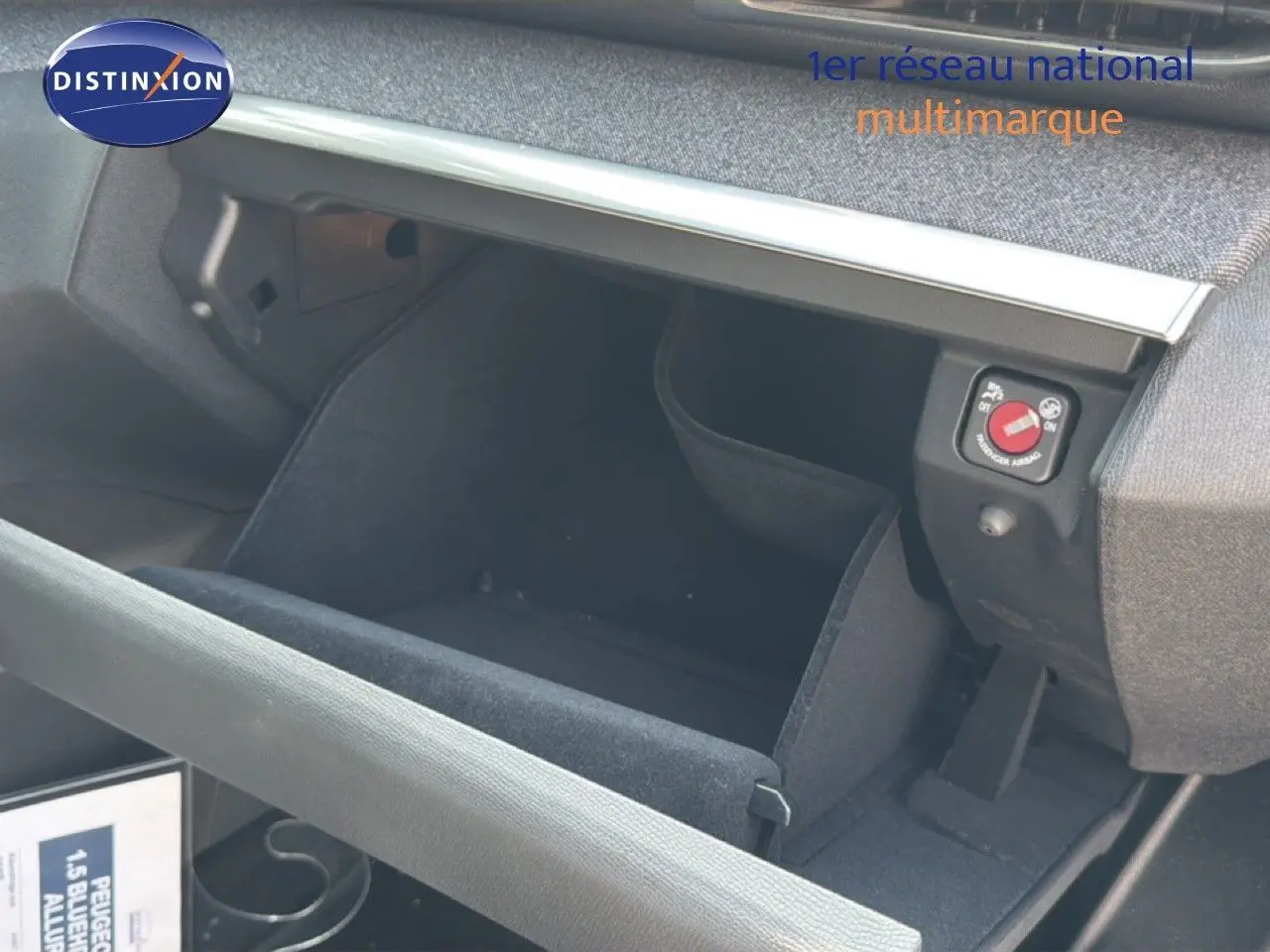 Intérieur du Peugeot 5008 2023 montrant la boîte à gants ouverte avec revêtement noir et détails de commande airbag.