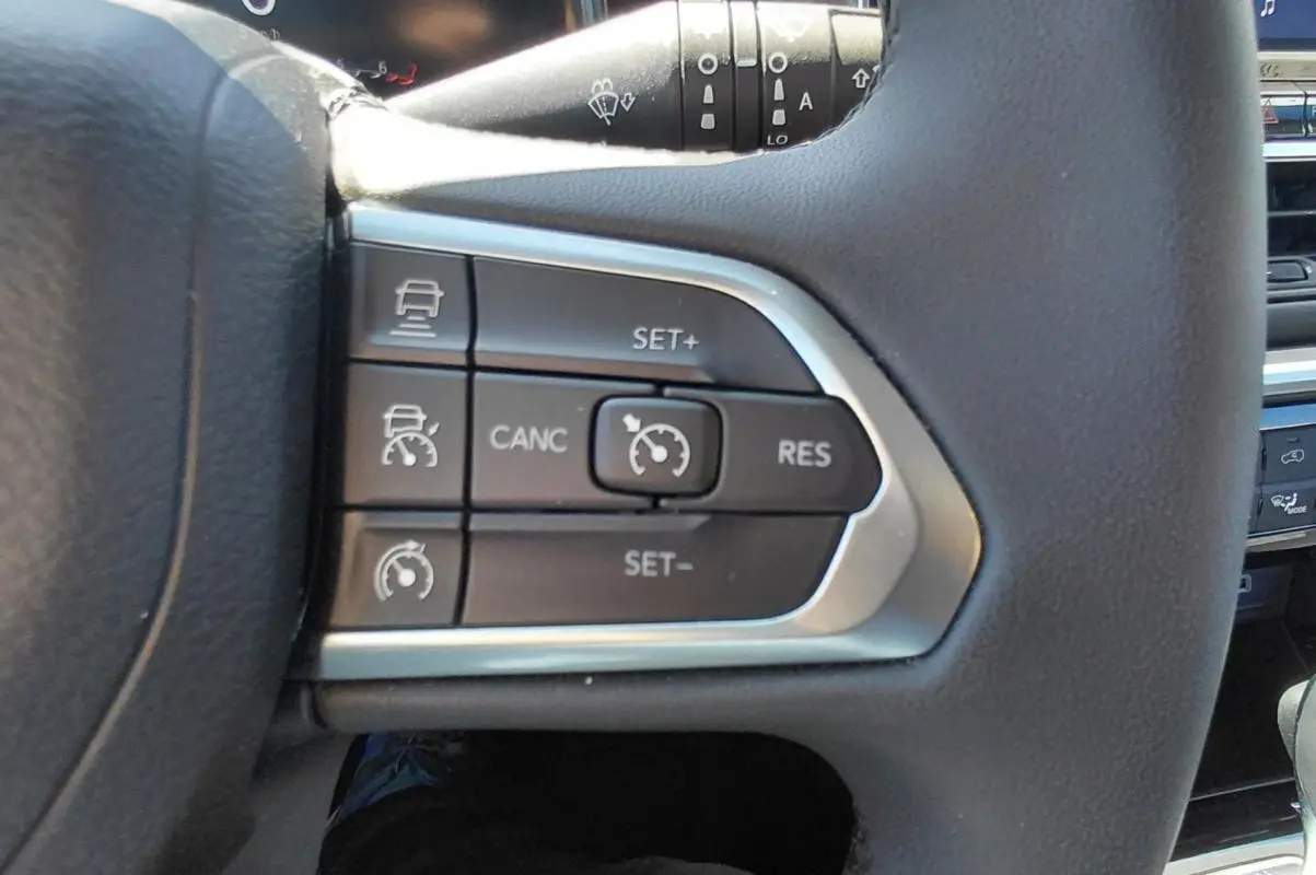 Gros plan sur les commandes du régulateur de vitesse au volant du Jeep Compass bleu 2025.