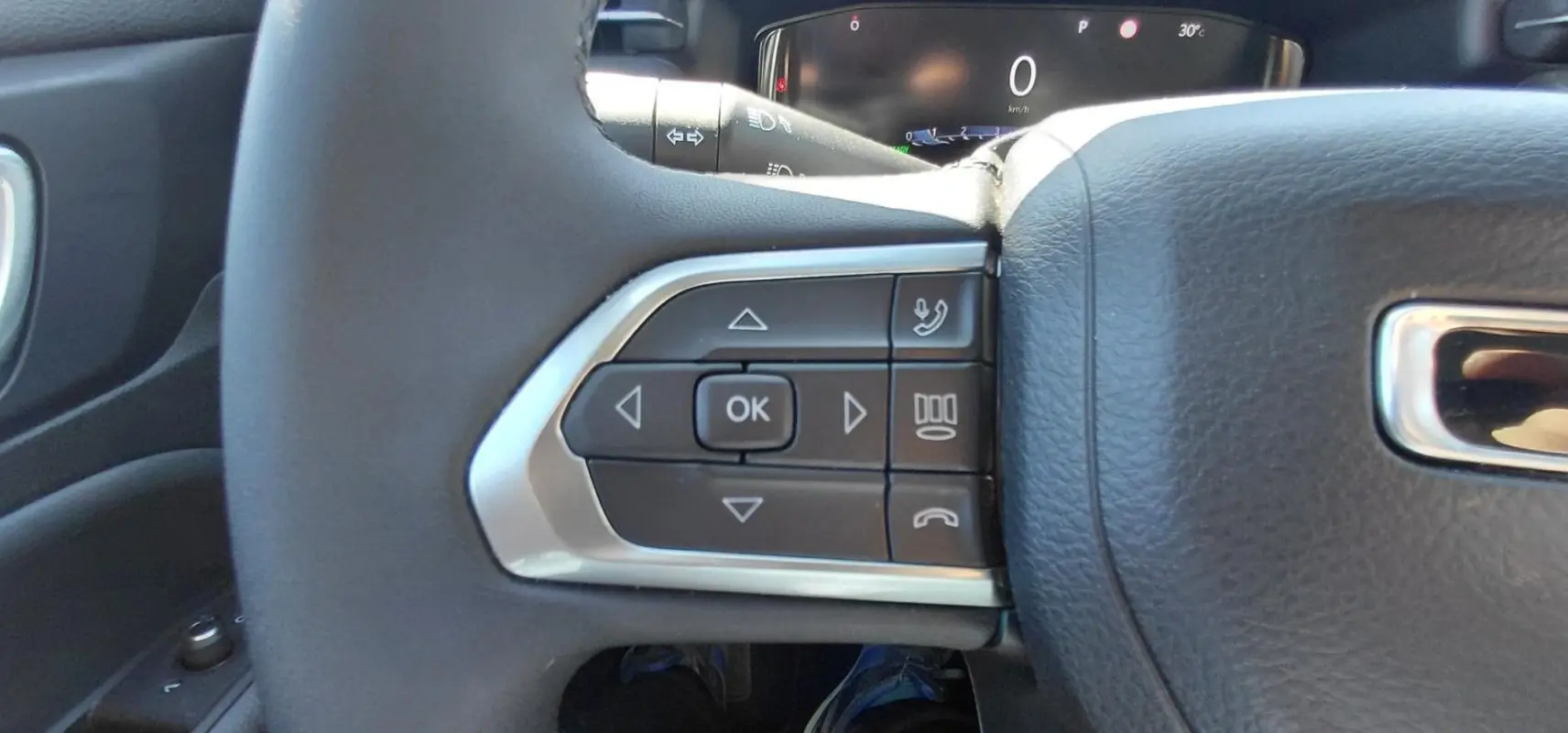 Gros plan sur les commandes gauche du volant du Jeep Compass 2025, montrant les boutons multifonctions noirs et argentés.