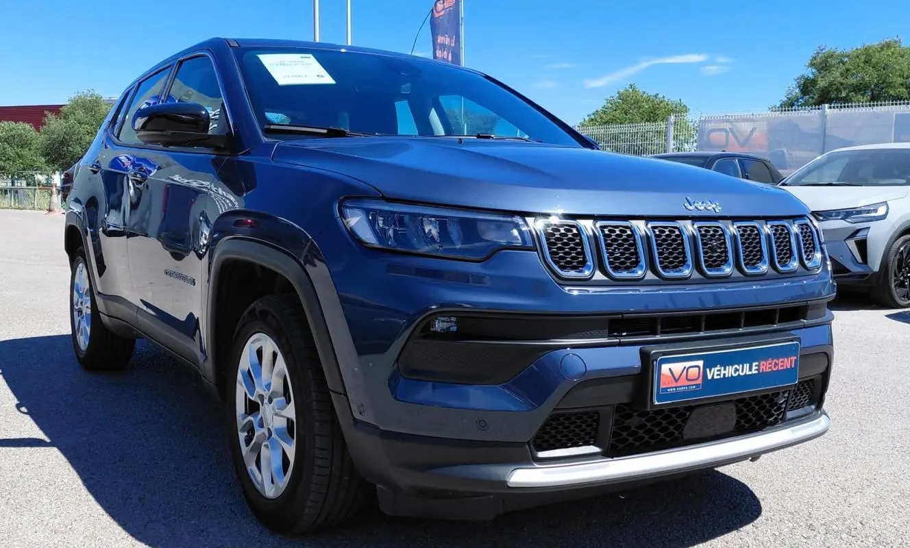 Jeep Compass bleu en 3/4 avant droit, avec calandre distinctive et jantes alliage 18 pouces visibles.